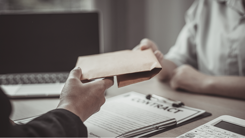 A person handing an envelope over a contract document